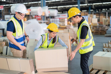 Staff in large storage warehouse together packing goods and carry carton box on pallet