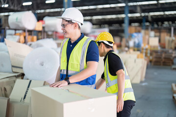 Staff in large storage warehouse together packing goods and carry carton box on pallet
