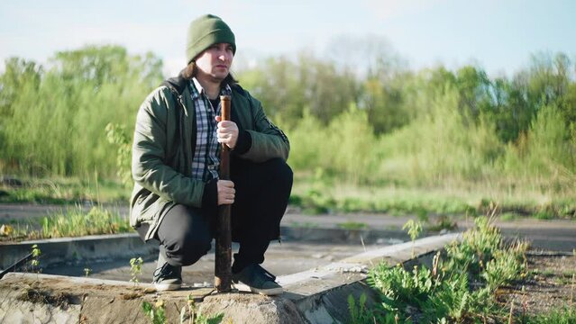 The guy with the baseball bat is squatting down and looking around. He's obviously waiting for someone