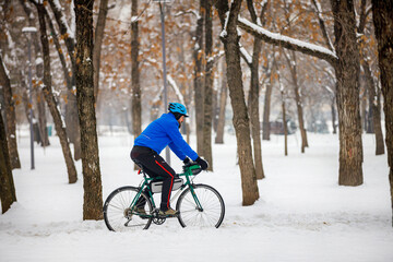 A bearded man rides a bicycle in a winter park. Eco-friendly transport in winter. Active lifestyle