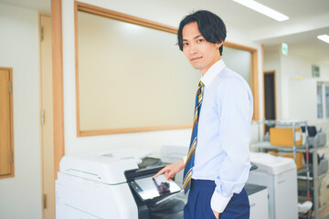 会社でコピー機を操作する若い男性