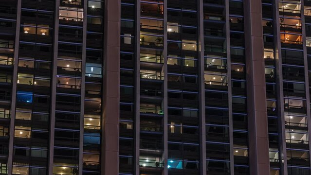 Big glowing windows in modern office and residential buildings timelapse at night, in rows of windows light shines. Many blocks of apartments