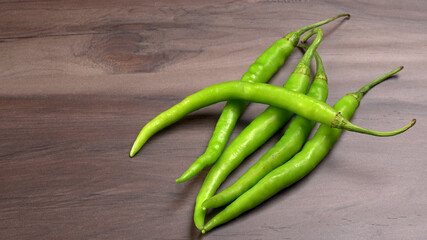 Fresh long Indian green chillies on wooden background.
