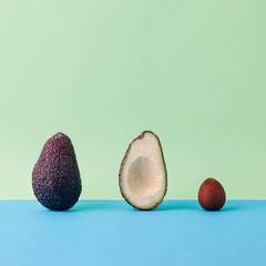 Stages of life. Avocado from outside, sliced and inside. Fruit seed, crust and cross section. Square composition on pastel green and blue.