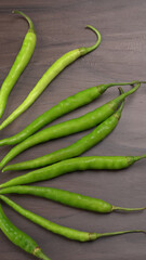 Fresh long Indian green chillies on wooden background.