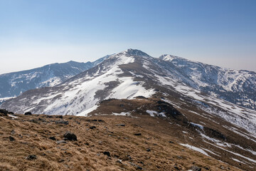 Panoramic aerial view from Schusterleiten of snow capped mountain peaks of Zirbitzkogel and Kreiskogel, Seetal Alps, Styria (Steiermark), Austria, Europe. Idyllic hiking trail in sunny early spring