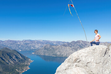 Woman with scenic view from Pestingrad (Derinski Vrh) of Kotor bay in sunny summer, Adriatic Mediterranean Sea, Montenegro, Balkan, Europe. Fjord winding along coastal towns. Lovcen, Orjen mountains