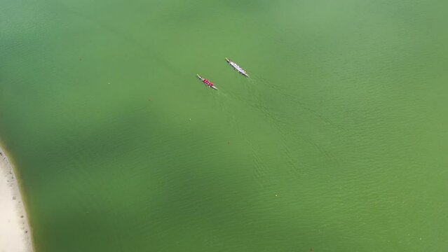 Video of a drone flying over two boats competing on a wide river