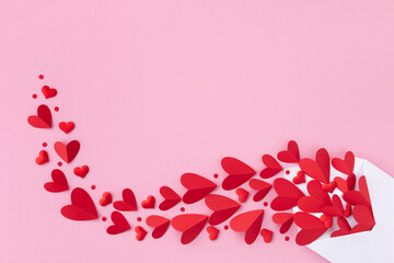 Creative composition on Saint Valentine day. Envelope and various red hearts for love romantic message on pink background. Flat lay..