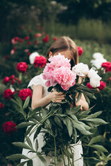the girl is holding a large bouquet of peonies