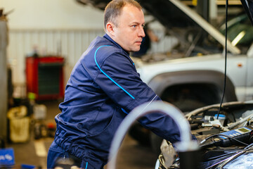 People occupation and business job. Automobile mechanic repairman repairing a car engine automotive workshop with a wrench, car service and maintenance. Repair service.