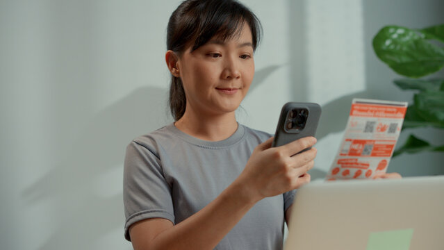 Female's hands using smart phone scan QR code on bill to pay online at home.