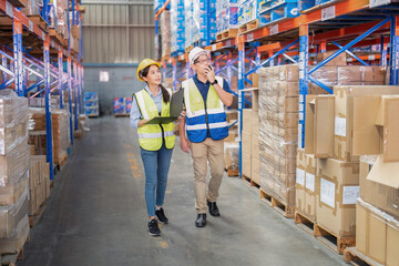 2 Staff in large depot storage warehouse manager and trainee walking check goods on shelf and radio