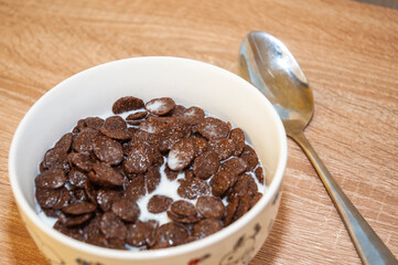 Chocolate cereal balls with milk on a wooden background. Top view.
