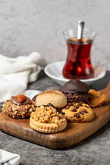 Sweet cookies on a dark background. Varieties of chocolate, hazelnut and pistachio cookies on a wooden serving plate. close up