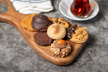 Sweet cookies on a dark background. Varieties of chocolate, hazelnut and pistachio cookies on a wooden serving plate. close up