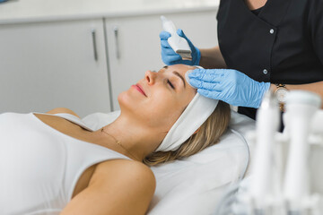 Side-view of a face of a woman laying down with her eyes cosed and smiling during microdermabrasion...