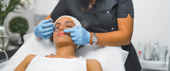 Medium shot of a woman receiving a collagen injection. Lip filer. Aesthetic medicine concept....