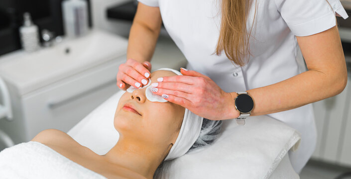 High-angle Shot Of A Woman In A Towel Laying Down While A Beautician Is Putting An Eye Compress On Her Face. Beauty Concept. High Quality Photo