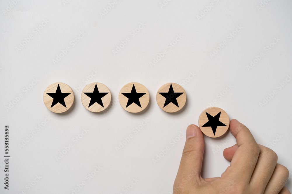 Poster hand holding black star which print screen on round wooden to give five stars for excellent evaluate