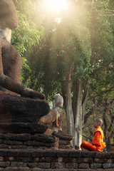 Buddhist monk and novice meditation in front of the Buddha statue at the old temple