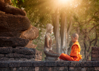 Buddhist monk and novice meditation in front of the Buddha statue at the old temple - obrazy, fototapety, plakaty