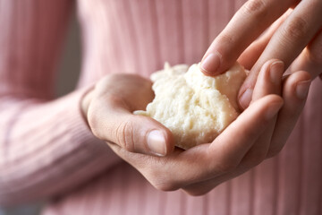 Woman in pink top holding raw shea butter or karite