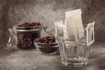 Making drip coffee with a special taste against the background of coffee beans. Drip coffee bag in a coffee cup. Trends in brewing coffee at home.Drip coffee filter. Flatley. Copy space. Place for tex