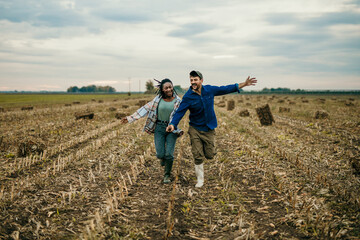 Loving couple running through the field in the countryside. 