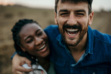 Close up portrait of a loving multiethnic couple having a big smile while spending time outdoors in nature.