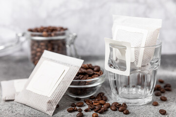 Making drip coffee with a special taste against the background of coffee beans. Drip coffee bag in a coffee cup. Trends in brewing coffee at home.Drip coffee filter. Flatley. Copy space. Place for tex