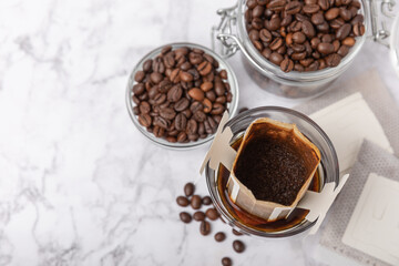 Making drip coffee with a special taste against the background of coffee beans. Drip coffee bag in a coffee cup. Trends in brewing coffee at home.Drip coffee filter. Flatley. Copy space. Place for tex