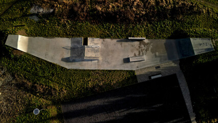 Skateboard park with concrete cement surface with concrete skateboard obstacles is designed for roller sports. Cycling is not allowed except for freestyle bikes.  winter morning sunrise, above, high