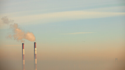 smoking pipes of a heating plant against the background of the sky during fog