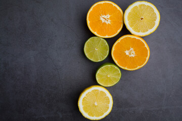 Fototapeta na wymiar Fresh ripe citruses. Lemons, limes and oranges on dark stone background. Top view
