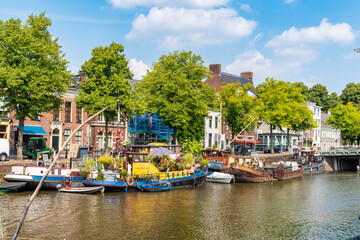 Fototapeta na wymiar Groningen, Netherlands-August 16, 2022: cityscape with old and colorful boats moored along the canal in the historic city center
