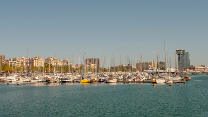 Fototapeta na wymiar Barcelona, Spain – July 19, 2012: Marina with yachts and boats in downtown of Barcelona at summer sunny hot day and blue sky during warm sunset colors.
