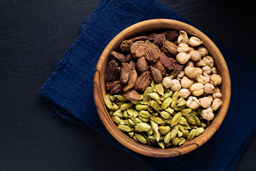 Food Spices concept 3 colors of cardamom pods green, black, white cardamom in wooden cup on black slate stone background with copy space