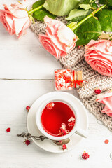 Fototapeta na wymiar The concept of romantic tea. Wrapped gift, hibiscus tea, a bouquet of delicate roses, sweets