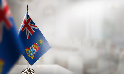 Small flags of the Cayman Islands on an abstract blurry background