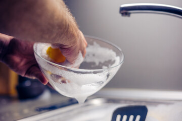 A brown glass plate in the hands of a man who is washing dishes in the kitchen.