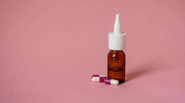 Spray nasal et médicament sur fond rose