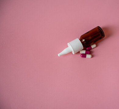 Spray nasal et m&eacute;dicament sur fond rose