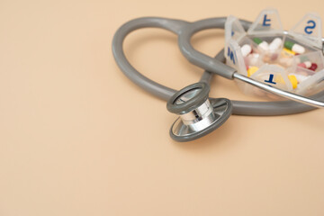 many colorful drug medicines or pill  in a pillbox with and  stethoscope on yellow table background, healthy and medicine concept