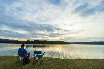 Fototapeta na wymiar The man sitting on the riverside watching the sunset.
