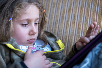 Little girl tired and sleepy playing with her tablet computer. Excessive tablet computer use in...