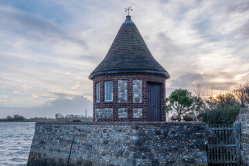 the round tower overlooking the harbour at Bosham West Sussex England with the sun setting and the sea in the background