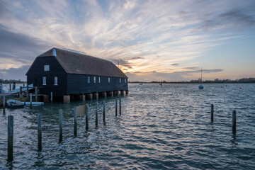 Raptackle wooden hut in Bosham West Sussex England over the sea with the sun going down in the background