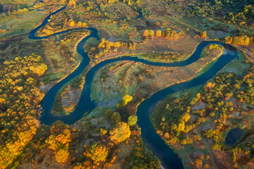 Aerial view of landscape of beautiful nature. Autumn morning above meadow and meadering river. Country roads on meadow.  