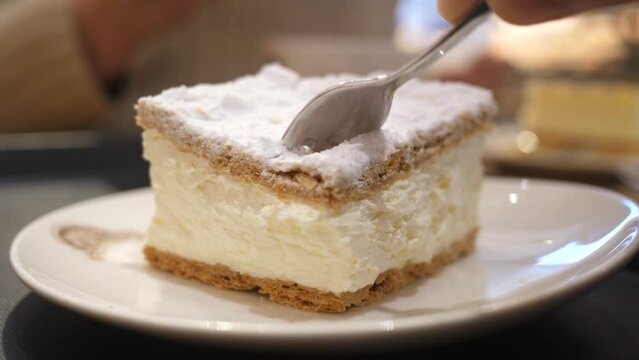 Person using fork eating a piece of sweet tasty cake pastry in bakery gastro bar closeup